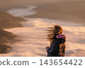 Woman watching sunrise above mountain valley 143654422