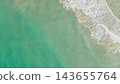 Aerial overhead photo of turquoise sea water with gentle white foam wave crashing on clear sandy shore in Greece for travel background design 143655764