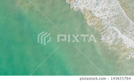 Aerial overhead photo of turquoise sea water with gentle white foam wave crashing on clear sandy shore in Greece for travel background design Aerial overhead photo of turquoise sea water with gentle white foam wave crashing on clear sandy shore in Greece for travel background design 143655764