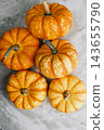 Flat lay composition of mini orange decorative pumpkins placed together on grey marble background for autumn season, Thanksgiving, or Halloween design 143655790