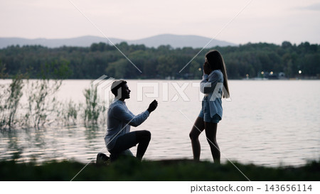 Man proposing marriage to woman by a lake at sunset Man proposing marriage to woman by a lake at sunset 143656114