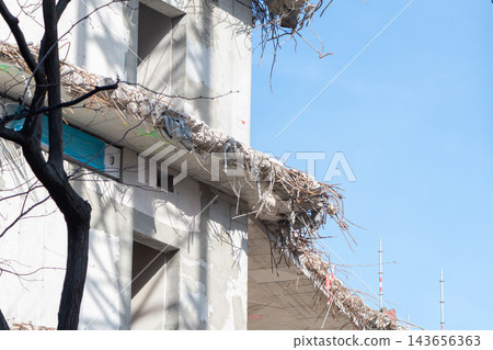 Damaged unfinished concrete building with exposed rebar against clear blue sky Damaged unfinished concrete building with exposed rebar against clear blue sky 143656363