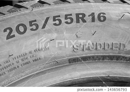 Close-Up of 205-55 R16 Studded Winter Tire Sidewall Showing Tire Size Markings and Metal Studs Close-Up of 205-55 R16 Studded Winter Tire Sidewall Showing Tire Size Markings and Metal Studs 143656793