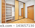 Modern sliding door wardrobe in apartment hallway interior with view to entrance door 143657130