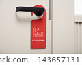 Closeup of red do not disturb sign hanging on black door handle in hotel 143657131