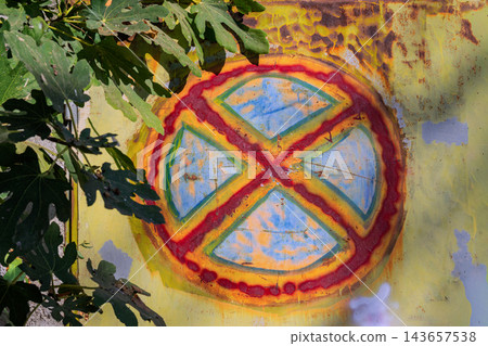 Hand painted no parking traffic sign on weathered metal surface. Close-up of hand painted No Stopping traffic sign on rusty yellow metal door surrounded by green fig tree leaves Hand painted no parking traffic sign on weathered metal surface. Close-up of hand painted No Stopping traffic sign on rusty yellow metal door surrounded by green fig tree leaves 143657538