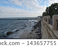 Scenic sea coastline with stone promenade and breaking waves on sand beach. 143657755