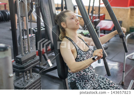 A woman with cerebral palsy exercises on a machine in a gym. 143657823