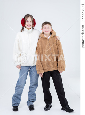 Two happy children wearing warm jackets, smiling, standing closely Two happy children wearing warm jackets, smiling, standing closely 143657971