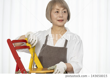 一位老婦人在客廳裡製作椅子,這是她的DIY愛好。 一位老婦人在客廳裡製作椅子,這是她的DIY愛好。 143658015