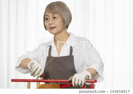 一位老婦人在客廳裡製作椅子,這是她的DIY愛好。 一位老婦人在客廳裡製作椅子,這是她的DIY愛好。 143658017