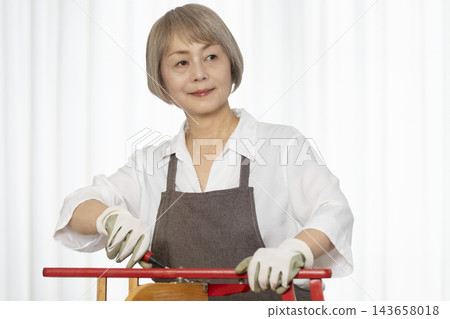 一位老婦人在客廳裡製作椅子,這是她的DIY愛好。 一位老婦人在客廳裡製作椅子,這是她的DIY愛好。 143658018