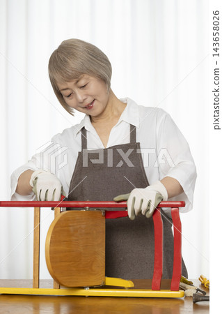 一位老婦人在客廳裡製作椅子，這是她的DIY愛好。 143658026