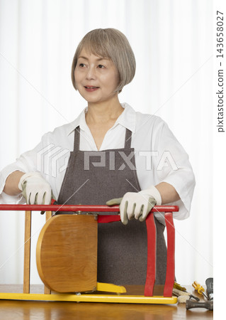 一位老婦人在客廳裡製作椅子,這是她的DIY愛好。 一位老婦人在客廳裡製作椅子,這是她的DIY愛好。 143658027