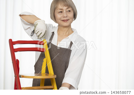 一位老婦人在客廳裡製作椅子,這是她的DIY愛好。 一位老婦人在客廳裡製作椅子,這是她的DIY愛好。 143658077