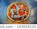 Raw chicken drumsticks marinated with sliced carrots and onions in an enamel bowl. 143658120