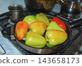 Fresh bell peppers frying in a skillet on a gas stove grill. 143658173