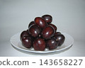 Heap of ripe purple plums served on a white ceramic plate. 143658227