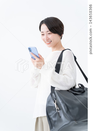 A woman going out with a large bag and her smartphone A woman going out with a large bag and her smartphone 143658366