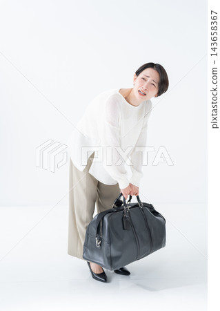 一名女子提著一個沉重的包包 143658367
