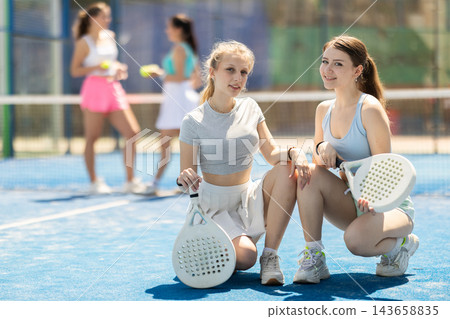 Women sitting with rackets on the court Women sitting with rackets on the court 143658835