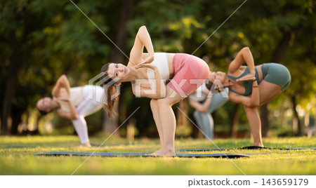 Fitness, sport and healthy lifestyle concept: girls doing yoga yoga pose - vrikshasana pose on mat in sunny summer park Fitness, sport and healthy lifestyle concept: girls doing yoga yoga pose - vrikshasana pose on mat in sunny summer park 143659179