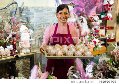 Portrait of a positive saleswoman standing with Christmas balls on a tray 143659195