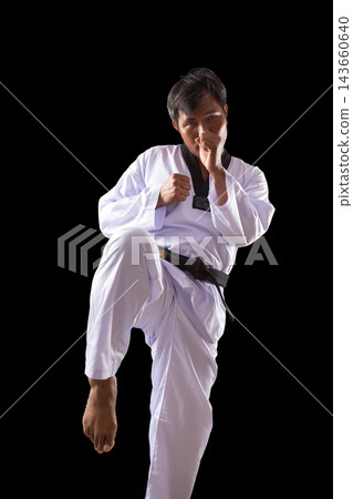Martial artist raising knee in fighting stance wearing white uniform and black belt, showing taekwondo, combat, strength, balance, discipline and focused athletic training Martial artist raising knee in fighting stance wearing white uniform and black belt, showing taekwondo, combat, strength, balance, discipline and focused athletic training 143660640