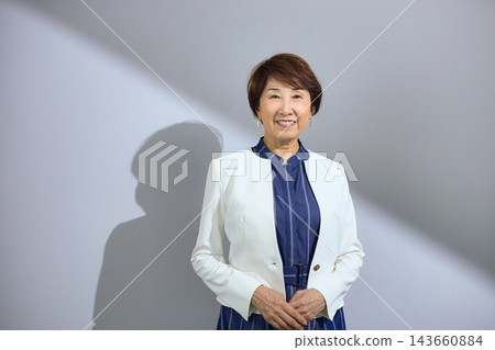 一位六十多歲、穿著外套、笑容燦爛的可愛女士。 143660884