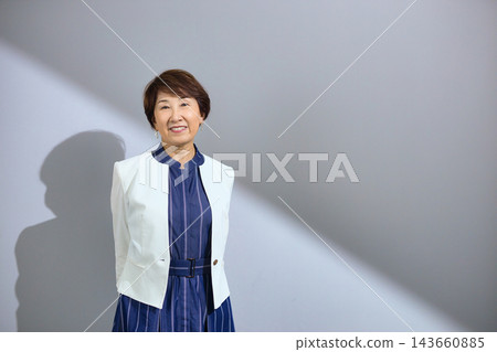 一位六十多歲、穿著外套、笑容燦爛的可愛女士。 一位六十多歲、穿著外套、笑容燦爛的可愛女士。 143660885