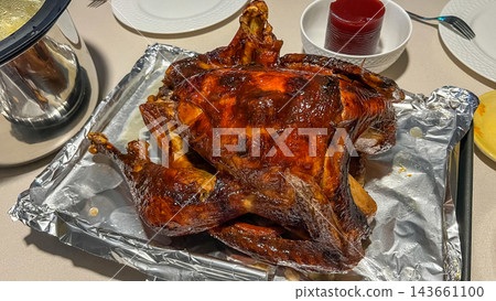 Caramelized Thanksgiving turkey glazed with maple syrup on a silver tray, surrounded by festive dining elements and a cozy indoor setting Caramelized Thanksgiving turkey glazed with maple syrup on a silver tray, surrounded by festive dining elements and a cozy indoor setting 143661100
