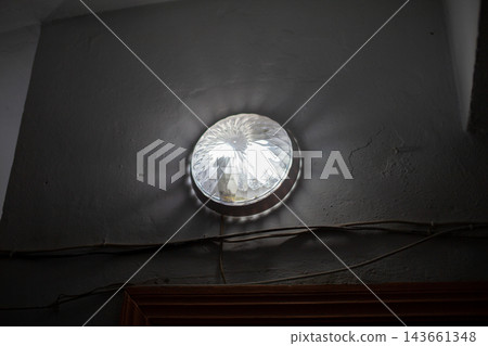 Round ceiling light fixture with a crystal pattern casts light and shadows on a gray wall, highlighting the texture and indoor environment Round ceiling light fixture with a crystal pattern casts light and shadows on a gray wall, highlighting the texture and indoor environment 143661348