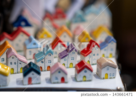 Miniature ceramic houses with colorful roofs are arranged in a display, featuring intricate details and a blurred background for depth Miniature ceramic houses with colorful roofs are arranged in a display, featuring intricate details and a blurred background for depth 143661471