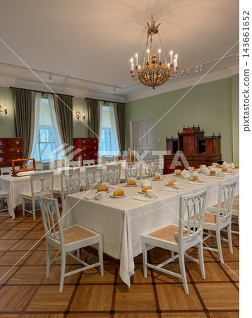 Elegant dining room features white tablecloths, wooden furniture, and a chandelier, creating a sophisticated atmosphere in a historic setting Elegant dining room features white tablecloths, wooden furniture, and a chandelier, creating a sophisticated atmosphere in a historic setting 143661652