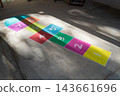 Colorful hopscotch game with numbers painted on concrete floor illuminated by sunlight and shadows 143661696