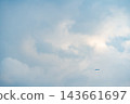 Distant small passenger airplane flying in the vast cloudy blue sky with large copy space 143661697