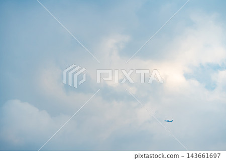 Distant small passenger airplane flying in the vast cloudy blue sky with large copy space Distant small passenger airplane flying in the vast cloudy blue sky with large copy space 143661697