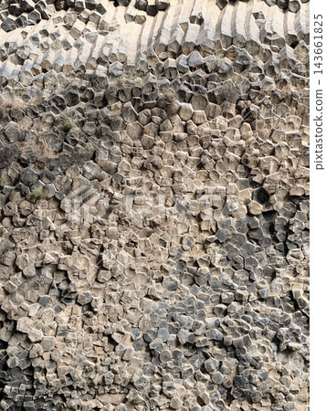 Densely packed angular rock fragments create a rugged gray and beige surface, showing layered textures, irregular shapes, and weathered mineral detail Densely packed angular rock fragments create a rugged gray and beige surface, showing layered textures, irregular shapes, and weathered mineral detail 143661825