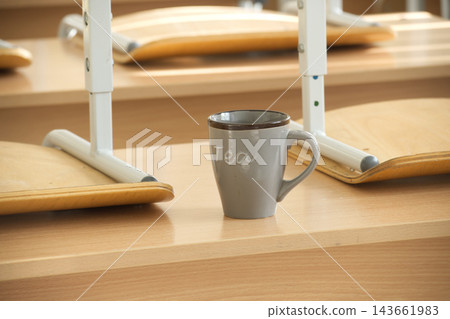 Gray Ceramic Tea Mug Placed on Wooden School Desk in Empty Classroom Environment Gray Ceramic Tea Mug Placed on Wooden School Desk in Empty Classroom Environment 143661983