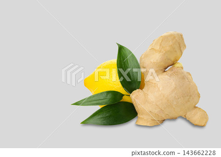Ginger root sits beside a fresh lemon and green leaves. Natural ingredients concept Ginger root sits beside a fresh lemon and green leaves. Natural ingredients concept 143662228