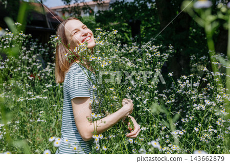 Happy Woman Holding a Bunch of Wild Daisy Flowers in a Summer Meadow Happy Woman Holding a Bunch of Wild Daisy Flowers in a Summer Meadow 143662879