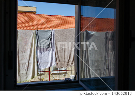 Towels Drying on Clothesline Outside Window, Mediterranean Home with Terracotta Roof Towels Drying on Clothesline Outside Window, Mediterranean Home with Terracotta Roof 143662913
