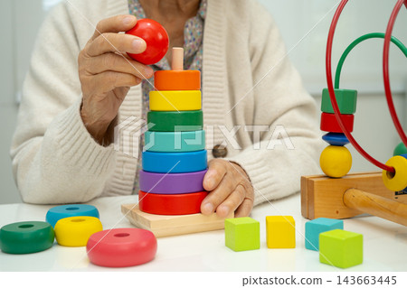 Asian elderly woman playing enhancing skill board game. Asian elderly woman playing enhancing skill board game. 143663445