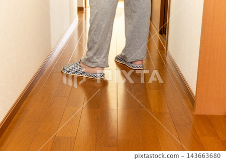 A person walking down the corridor wearing slippers. A person walking down the corridor wearing slippers. 143663680