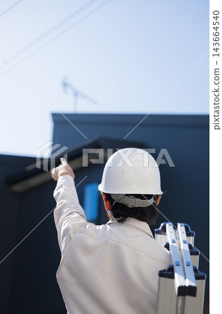Under the blue sky, workers point to the roof of a detached house to check the installation of a television antenna and perform equipment inspections. Under the blue sky, workers point to the roof of a detached house to check the installation of a television antenna and perform equipment inspections. 143664540