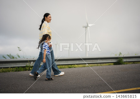 mother and preschool child girl holding hand and walking on a road on mountain in morning 143665815