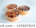 Three round kraft paper bowls with clear lids containing fried chicken over rice, shown on a neutral white background. Ideal for food delivery and restaurant packaging concepts. 143665824