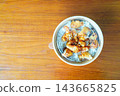 Top view of an Asian-style takeout meal with fried chicken over white rice in a round disposable container. The bowl is topped with sesame seeds and sits on a wooden table with copy space. 143665825