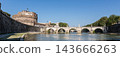 Panoramic view of the iconic Castel Sant'Angelo and Ponte Sant'Angelo spanning the Tiber River in Rome, Italy, under a clear blue sky on a bright sunny day 143666263