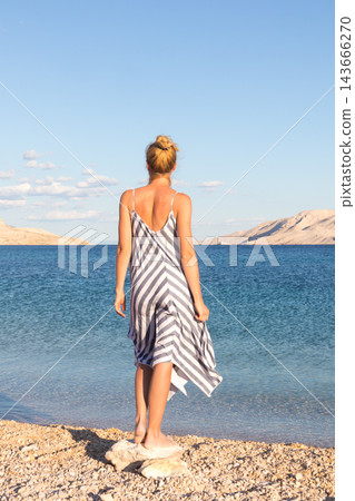 Happy carefree woman enjoying late afternoon walk on white pabbled beach on Pag island, Croatia. Happy carefree woman enjoying late afternoon walk on white pabbled beach on Pag island, Croatia. 143666270